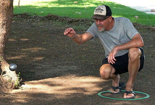 A p&eacute;tanque player tosses metal boules