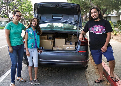 Girl Scout Troop 5604 stocks the back of their car with goods and supplies