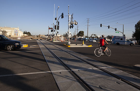 A cyclist waits for the traffic signal at the corner of Arrow Highway and E Street